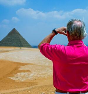 muž v růžovém tričku se dívá na pyramidy