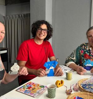 three women sitting at a table holding up cards
