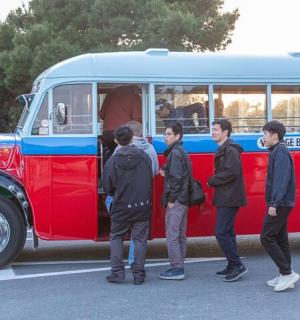 Skupina chlapců stojících před červenomodrý autobus