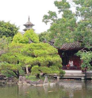 a building in a garden next to a pond
