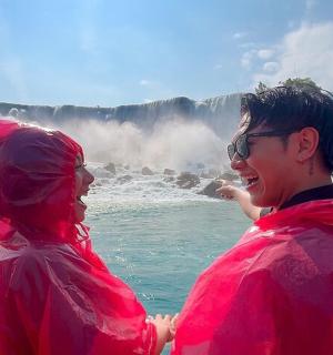 dva lidé v červených bundách stojící před vodopádem