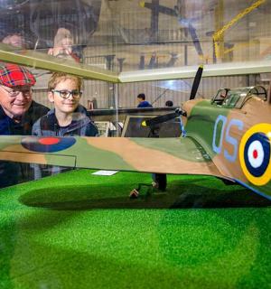 dos homes drets al costat d'un petit avió verd