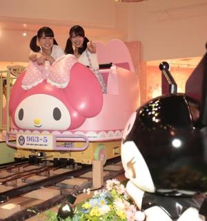 two girls riding on a toy train in a mall