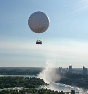 a hot air balloon flying over a waterfall