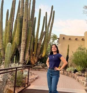 a woman standing on a path in front of a cactus