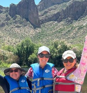 three people standing in a river with their arms in the air