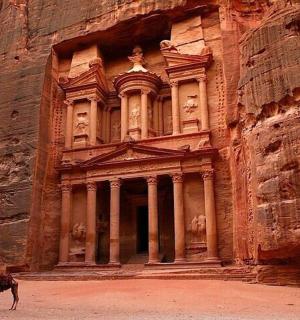 一头骆驼站在一座石头建筑前