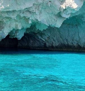 a large cave with blue water in front of it