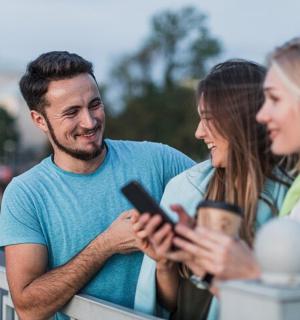 a man and two women looking at a cell phone
