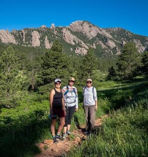 three people standing on a trail in the mountains