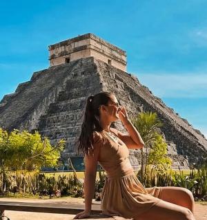 a woman in a dress sitting in front of the pyramid