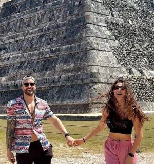 a man and woman holding hands in front of a pyramid