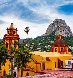 一座黄色的建筑,有一座钟楼和一座山