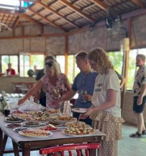 a group of people standing around a table with food