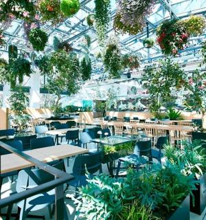 a greenhouse with tables and chairs and plants
