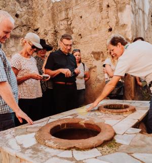 skupina lidí se dívá na muže, který vyrábí kamennou mísu