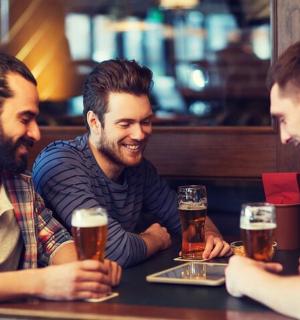 three men sitting at a table drinking beer