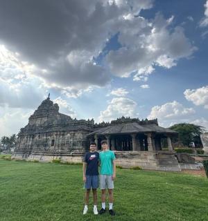two men standing in a field in front of a building