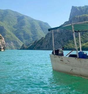 чамац у води са планинама у позадини