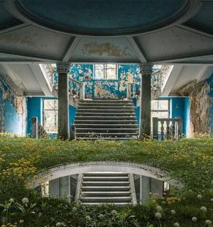 an abandoned building with stairs and flowers in front of it