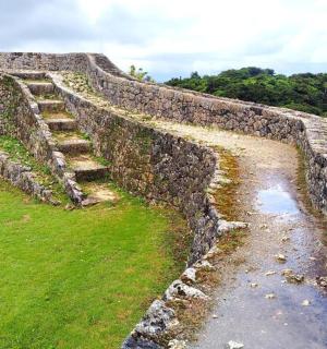 an old stone wall with stairs and grass