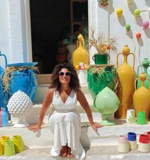 a woman sitting in front of a bunch of vases