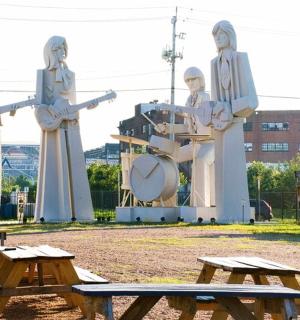 a statue of a group of women standing next to picnic tables