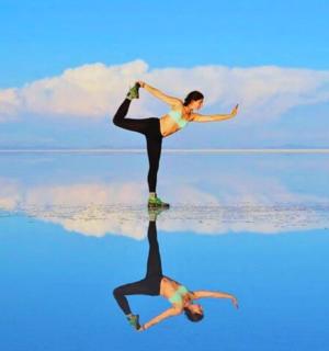 a woman doing yoga on the beach with her reflection in the water