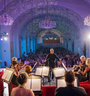 an orchestra in a large room with a crowd of people