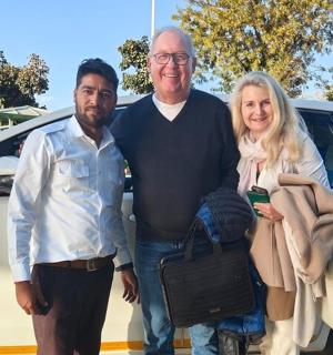 two men and a woman standing in front of a car