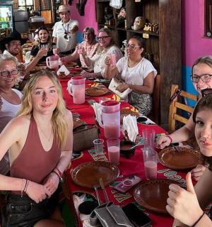 महिलाओं का एक समूह मेज पर बैठकर केक खा रहा है