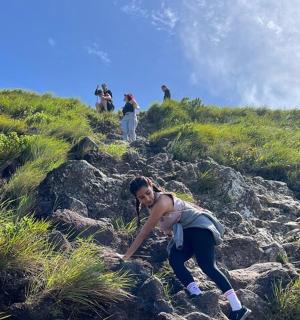 一名女子正在爬上一座长满草的山坡