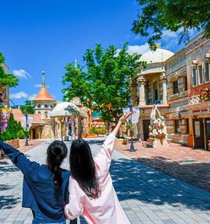 两名女子在游乐园里举起双臂站立