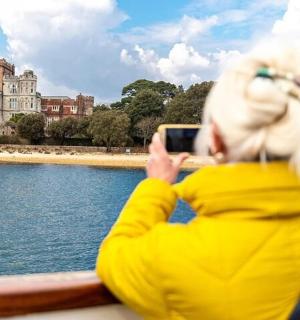 a woman taking a picture of a castle from a boat