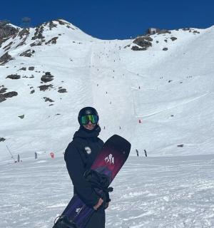 eine Person, die ein Snowboard auf einem schneebedeckten Berg hält