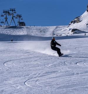 osoba jedoucí na snowboardu po zasněženém svahu