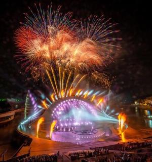 a fireworks show with a ferris wheel and a roller coaster