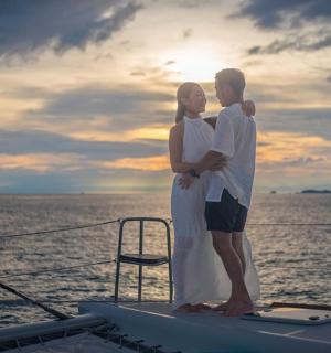 a man and woman standing on the bow of a boat
