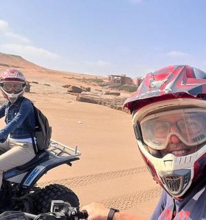 dva človeka, ki se vozita na umazanem motorju v puščavi