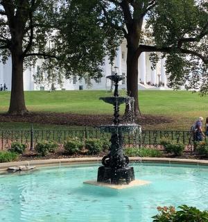 a fountain in a park with people walking around it