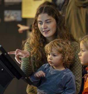 a woman and two children looking at a laptop computer