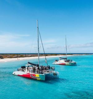 two boats in the water next to a beach