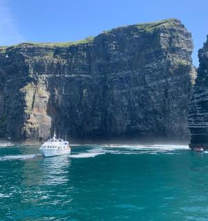a boat in the water next to a large cliff