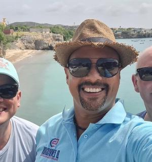 three men posing for a picture at the beach