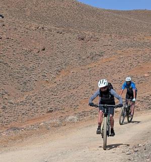 两个人骑着自行车沿着土路行驶