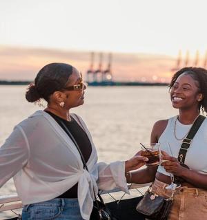 two women standing on a boat with drinks
