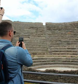 a man and woman taking pictures of an amphitheater