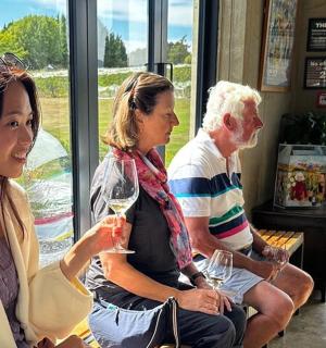 一群人坐在长凳上，手里拿着酒杯