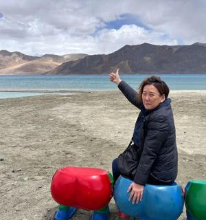 a woman is sitting on some play equipment on the beach