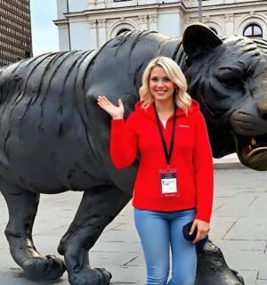 一位女士站在老虎雕像前